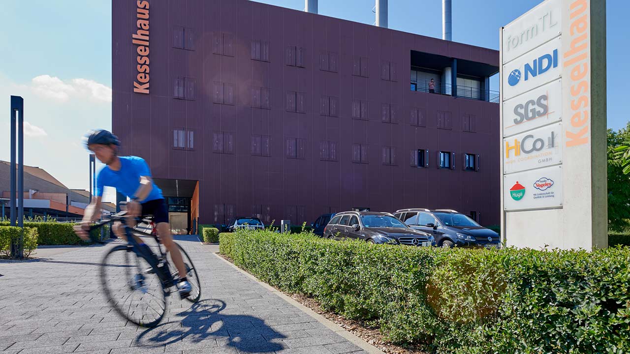 Radfahrer vor dem Kesselhaus Gebäude, Firmensitz von NDI Europe